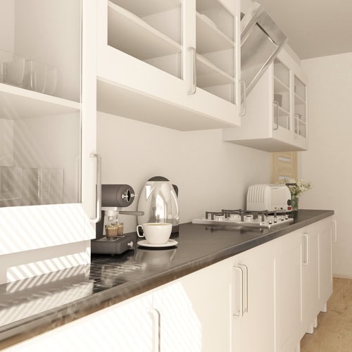 Cuina moderna amb armaris blancs, taulell negre, cafetera, bullidor d'aigua i torradora. Els armaris superiors tenen portes de vidre; La llum natural entra, fent ombres. Inspiració perfecta per a una reforma integral que combina funcionalitat amb estil.